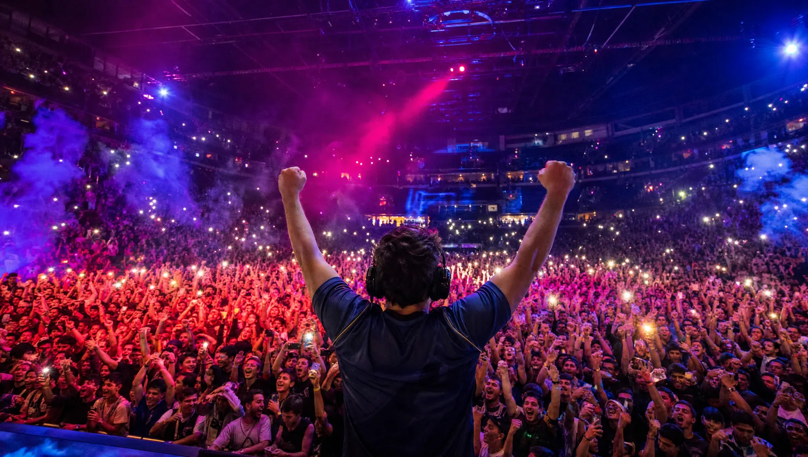 Arena de esports lotada, torcida com celulares acesos