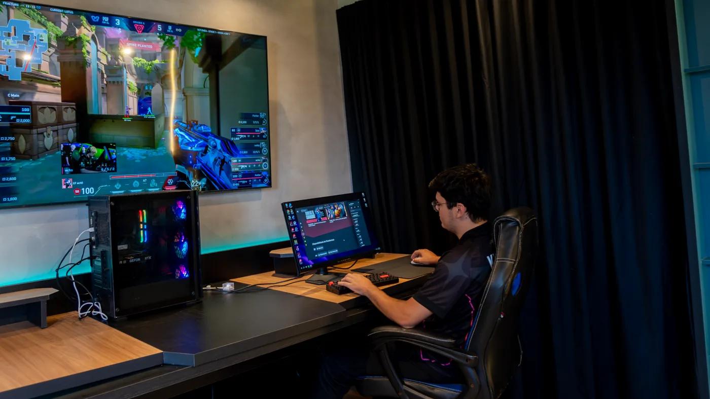 Player gravando no setup do Stellae Studio, telão com gameplay ao fundo